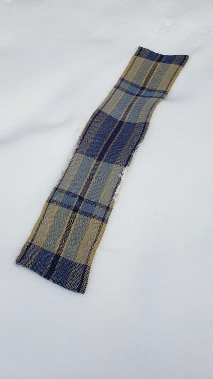 Handwoven plaid table runner on a blanket of snow.