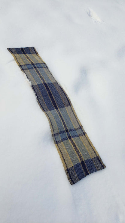 Handwoven plaid table runner on a blanket of snow.